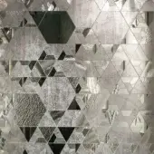 Grey mosaic surface with irregular fragments, displaying a geometric pattern of triangles, hexagons, and varied textures, set against a dark background.
